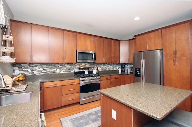 kitchen with sink, a center island, appliances with stainless steel finishes, a kitchen breakfast bar, and decorative backsplash