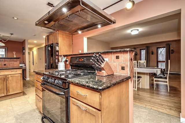 kitchen with dark stone countertops, backsplash, a center island, black appliances, and exhaust hood