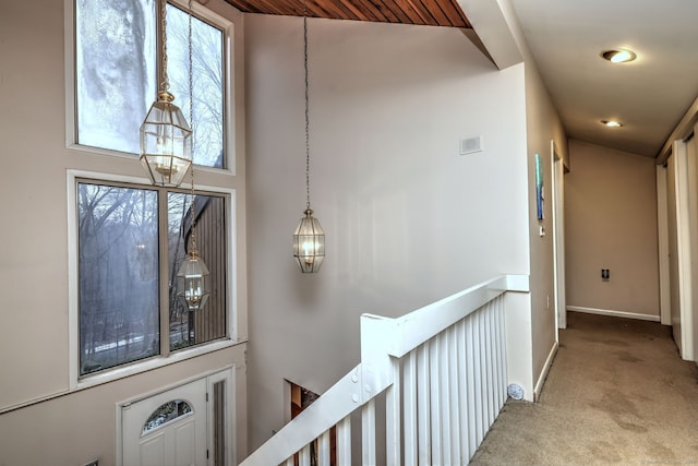 hallway featuring light carpet, a towering ceiling, and a chandelier