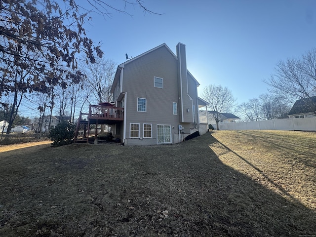 back of property with stairway, fence, a chimney, a deck, and a lawn