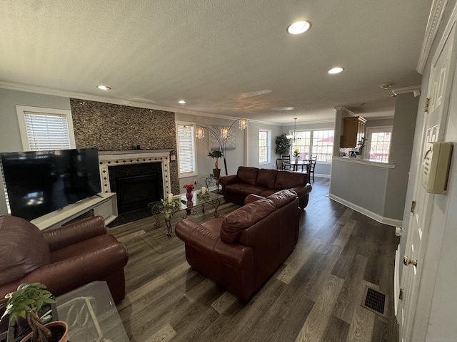 living room with visible vents, dark wood finished floors, ornamental molding, a notable chandelier, and a textured ceiling