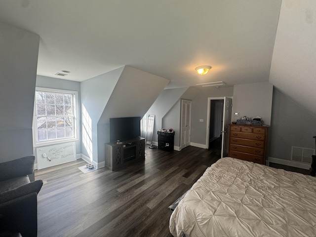 bedroom with vaulted ceiling, dark wood-style floors, visible vents, and baseboards