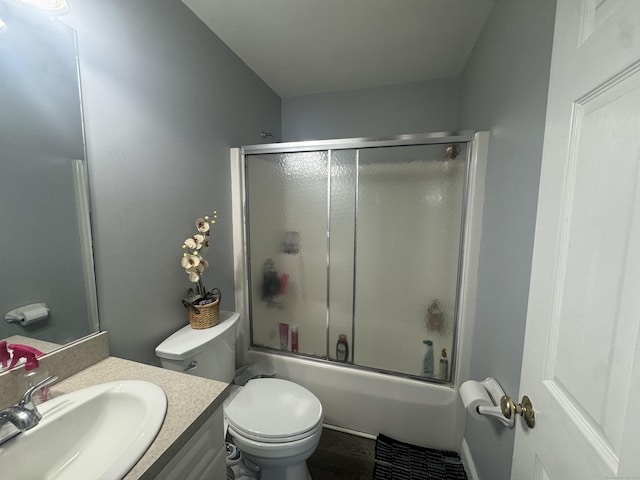 full bath with vanity, toilet, and bath / shower combo with glass door