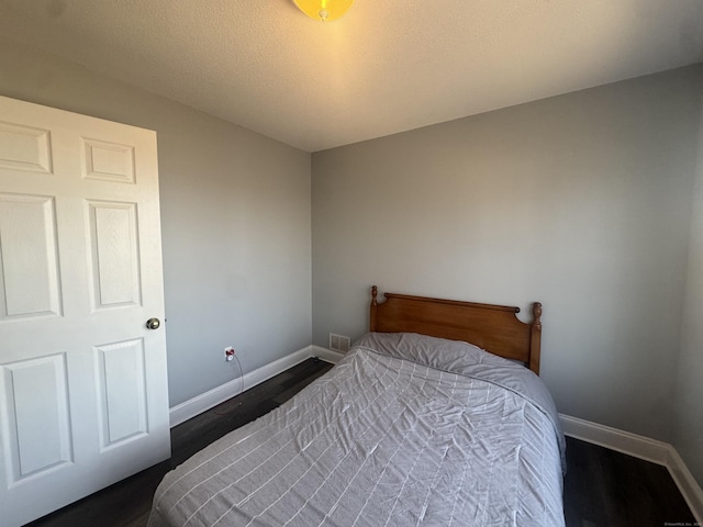 bedroom featuring baseboards and dark wood-style flooring