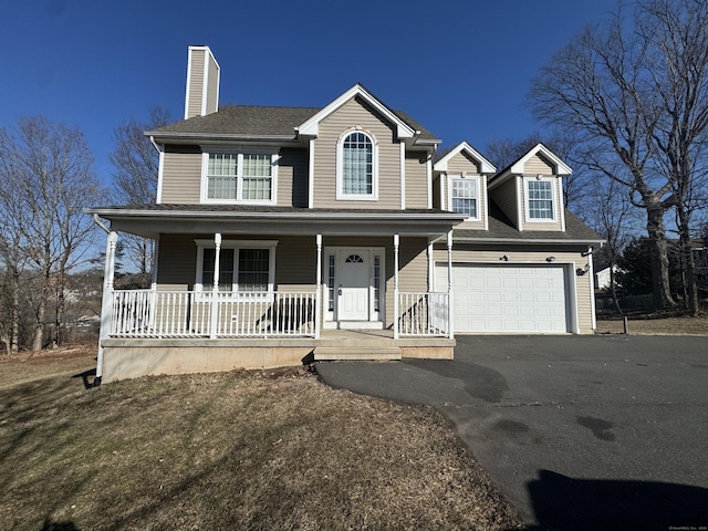 view of front of home featuring aphalt driveway, a porch, a chimney, and a shingled roof