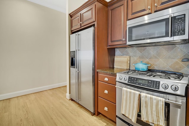 kitchen with stainless steel appliances, tasteful backsplash, crown molding, and light hardwood / wood-style floors