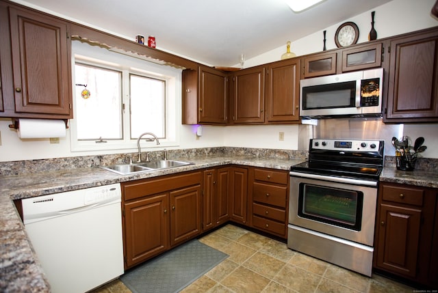 kitchen with vaulted ceiling, stainless steel appliances, and sink