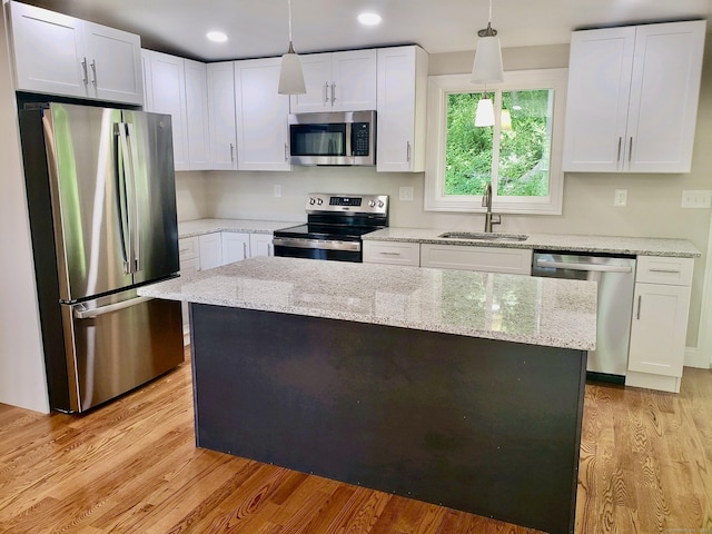 kitchen featuring sink, appliances with stainless steel finishes, hanging light fixtures, white cabinets, and a kitchen island