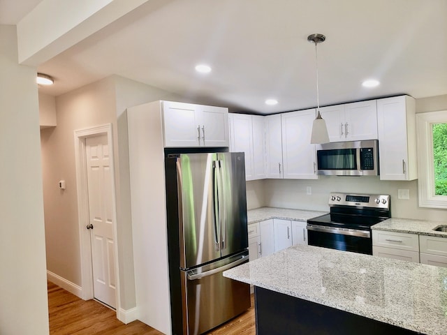 kitchen featuring white cabinetry, appliances with stainless steel finishes, decorative light fixtures, and light stone counters