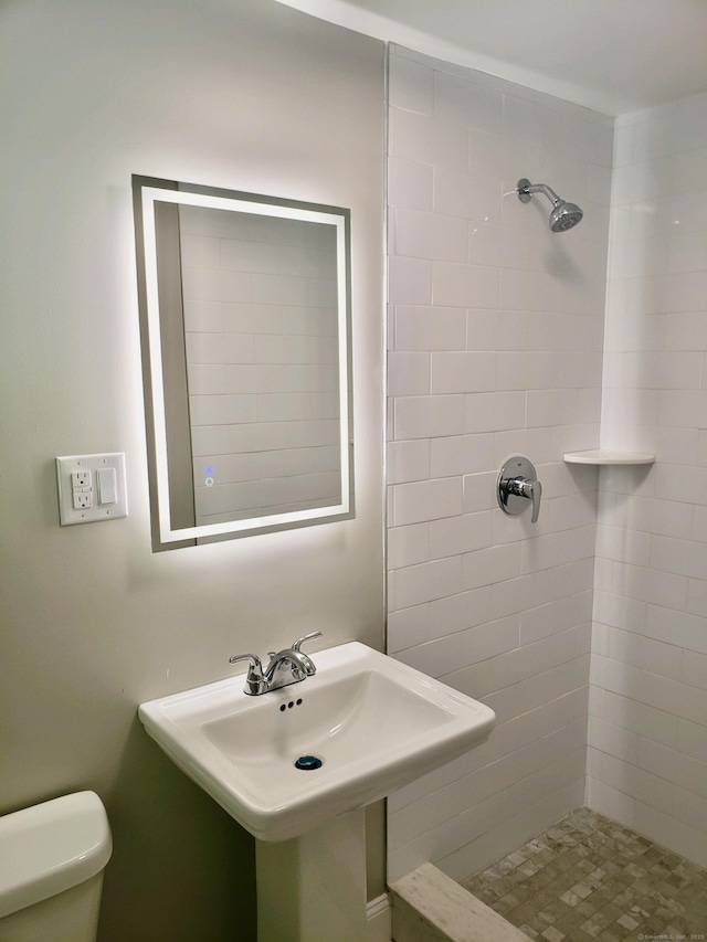 bathroom with toilet, sink, and a tile shower