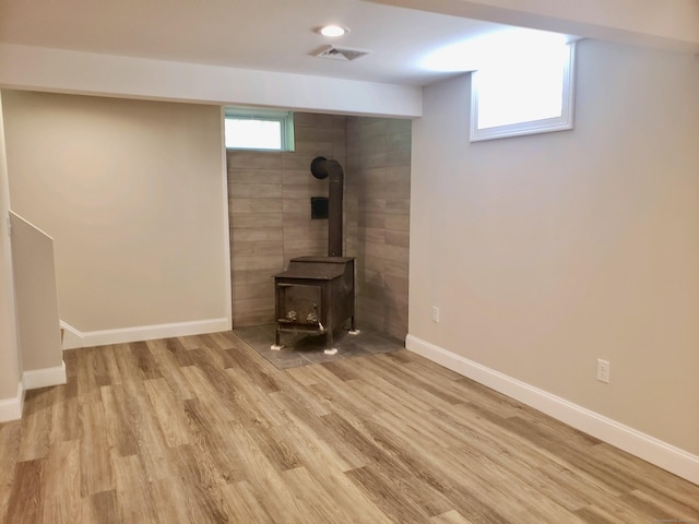 basement with a wood stove and light hardwood / wood-style floors