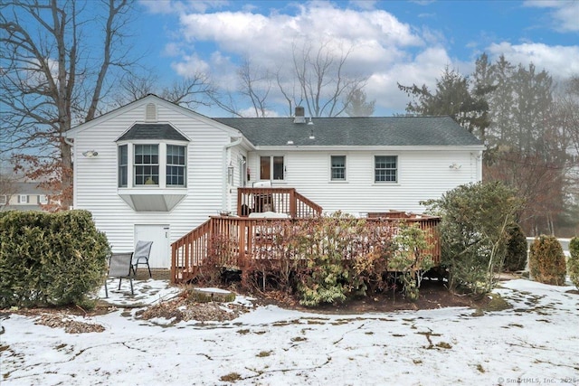 snow covered back of property featuring a deck