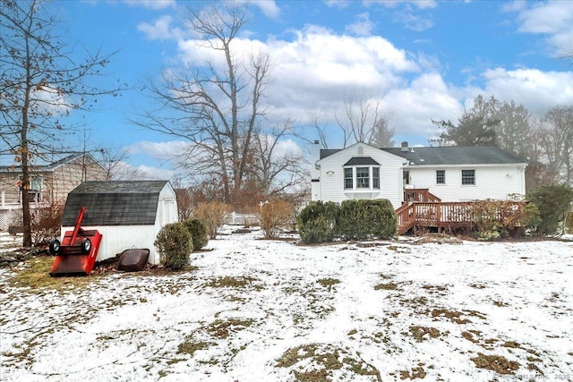 yard covered in snow with a storage shed and a deck