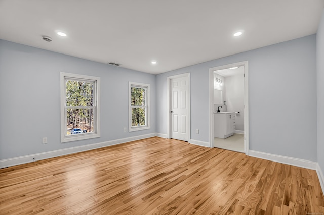 unfurnished bedroom with light hardwood / wood-style floors and ensuite bath