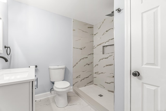 bathroom with vanity, toilet, and a tile shower