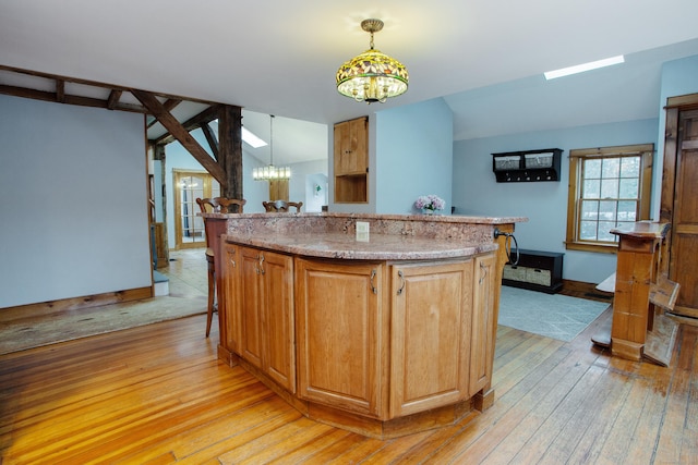 kitchen with decorative light fixtures, vaulted ceiling, a kitchen island, and a notable chandelier