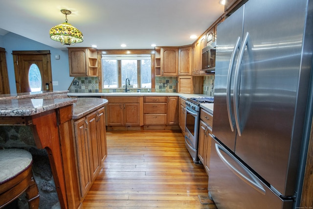 kitchen with sink, appliances with stainless steel finishes, backsplash, decorative light fixtures, and light wood-type flooring