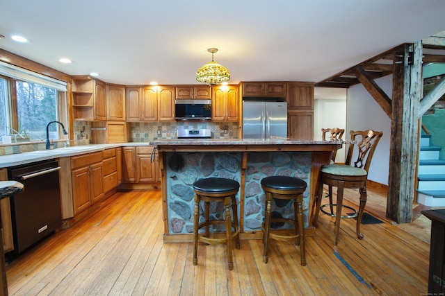 kitchen featuring stainless steel appliances, a kitchen bar, a center island, and sink