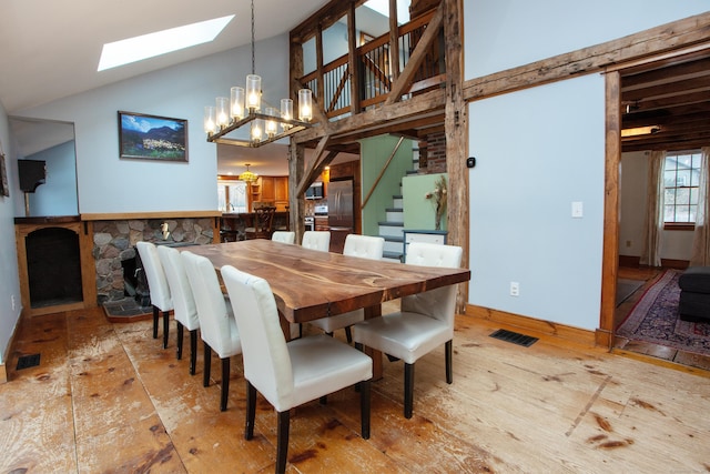 dining room featuring a fireplace, high vaulted ceiling, a chandelier, and light wood-type flooring