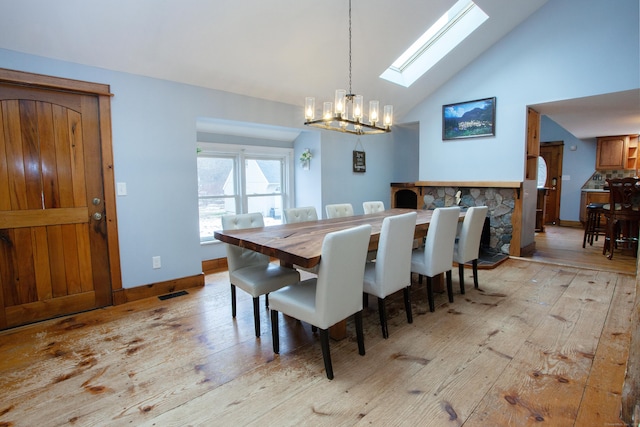 dining room with an inviting chandelier, high vaulted ceiling, and light hardwood / wood-style flooring