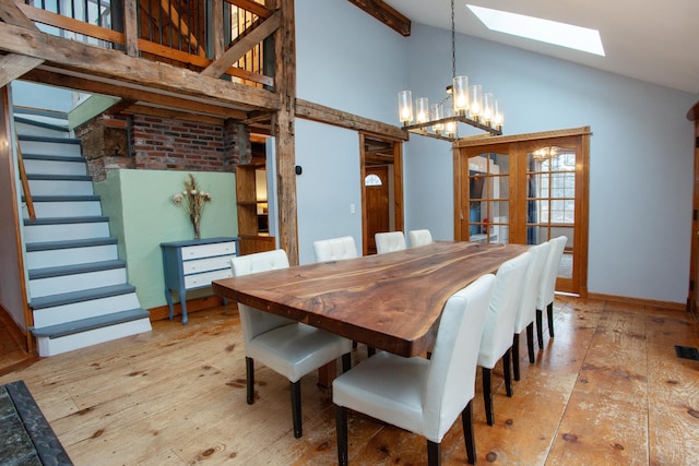 dining space with light hardwood / wood-style floors, an inviting chandelier, high vaulted ceiling, and a skylight