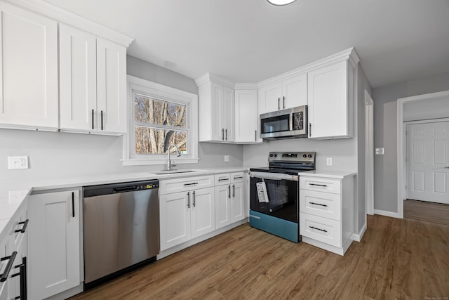 kitchen with white cabinetry, sink, hardwood / wood-style flooring, and appliances with stainless steel finishes