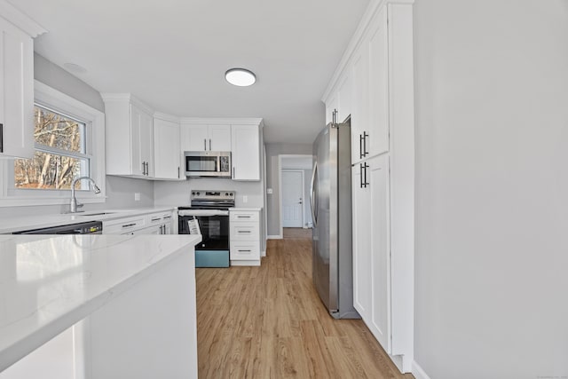 kitchen featuring sink, stainless steel appliances, light stone countertops, light hardwood / wood-style floors, and white cabinets