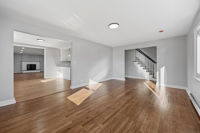 unfurnished living room with hardwood / wood-style flooring and a baseboard radiator