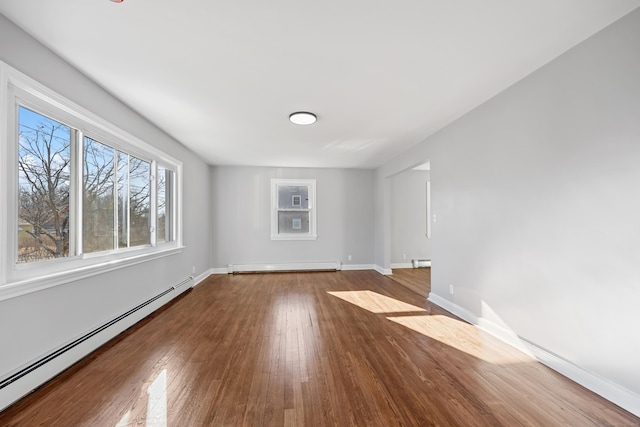 empty room with a baseboard heating unit and hardwood / wood-style floors