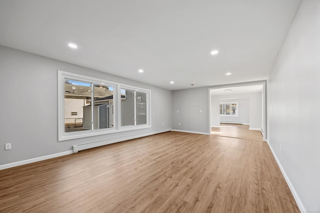 unfurnished living room featuring light hardwood / wood-style floors and a baseboard heating unit