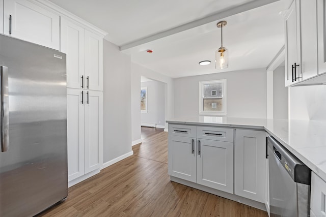 kitchen with appliances with stainless steel finishes, decorative light fixtures, white cabinets, hardwood / wood-style flooring, and light stone countertops