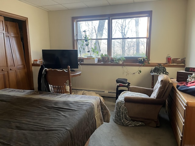 bedroom featuring multiple windows, a baseboard heating unit, carpet flooring, and a paneled ceiling