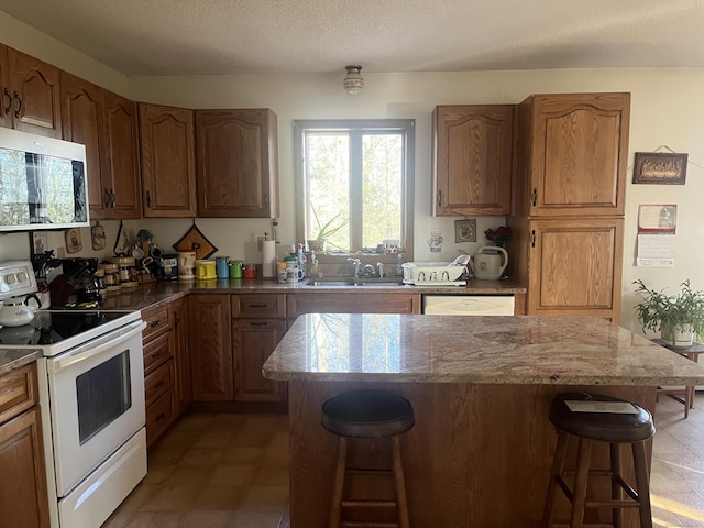 kitchen with sink, a kitchen island, a kitchen breakfast bar, and white electric range oven