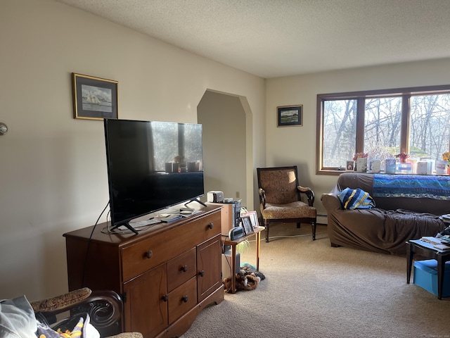 living room featuring a baseboard heating unit, light colored carpet, and a textured ceiling