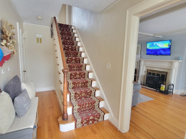 stairs featuring wood-type flooring and ornamental molding