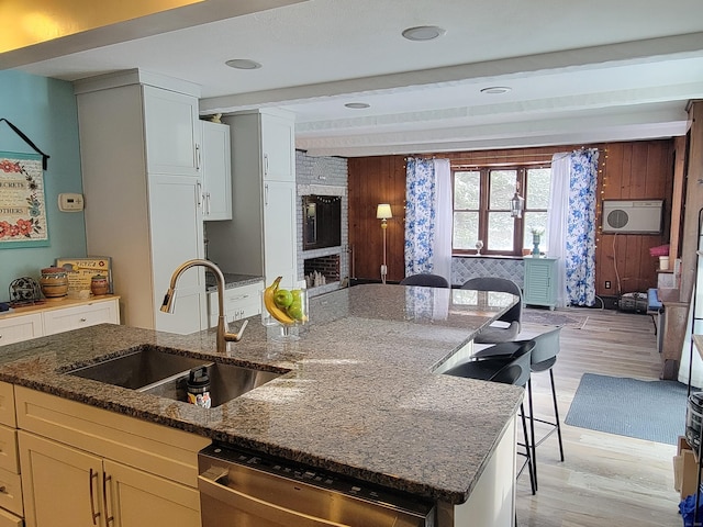 kitchen with dishwasher, sink, a kitchen bar, dark stone counters, and beam ceiling