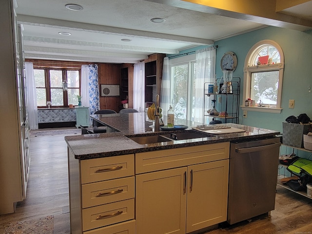 kitchen with beam ceiling, plenty of natural light, stainless steel dishwasher, and wood-type flooring