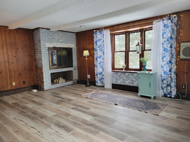 unfurnished living room featuring a fireplace, beamed ceiling, and wood-type flooring