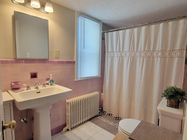 bathroom with radiator, tile walls, tile patterned flooring, toilet, and a textured ceiling