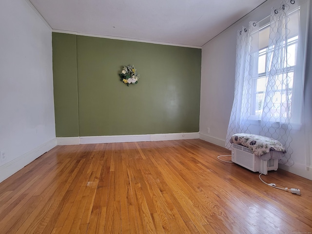 spare room featuring ornamental molding and light hardwood / wood-style floors