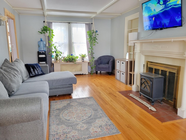 living room featuring hardwood / wood-style flooring, radiator heating unit, coffered ceiling, built in shelves, and a wood stove