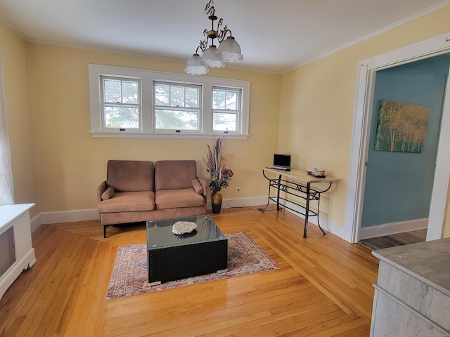 living room with crown molding, a chandelier, and light wood-type flooring