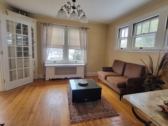 living room with ornamental molding, plenty of natural light, radiator heating unit, and an inviting chandelier