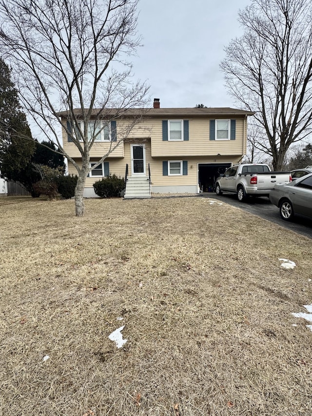 raised ranch with a garage and a front yard