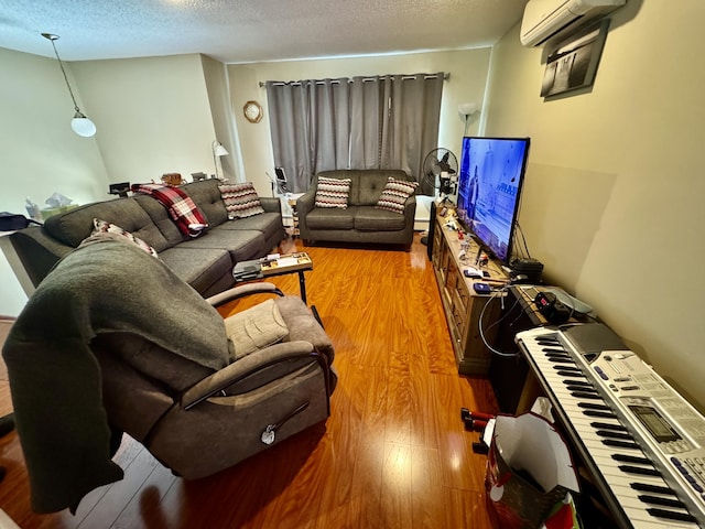 living room featuring hardwood / wood-style floors, a wall unit AC, and a textured ceiling