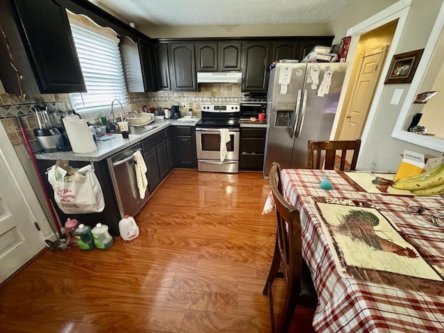 kitchen with stainless steel appliances, sink, decorative backsplash, and a textured ceiling