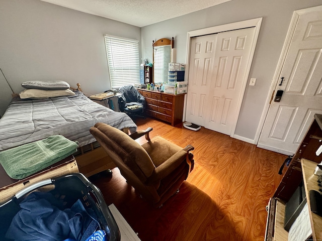 bedroom with wood-type flooring, a textured ceiling, and a closet