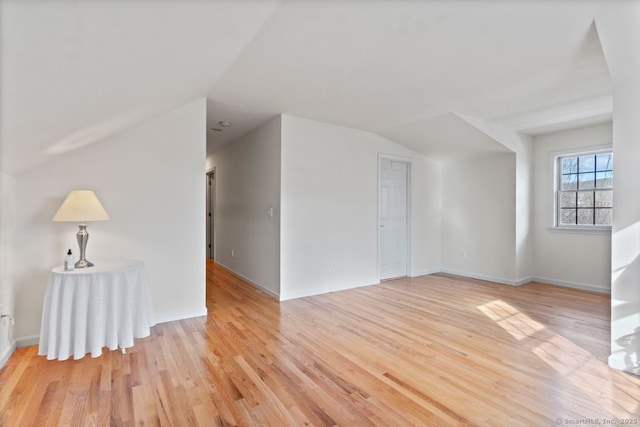 bonus room with vaulted ceiling and light wood-type flooring