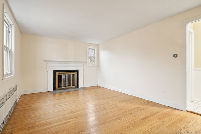 unfurnished living room featuring radiator heating unit and light wood-type flooring