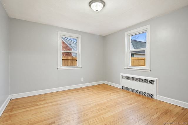 empty room featuring radiator heating unit and light hardwood / wood-style flooring